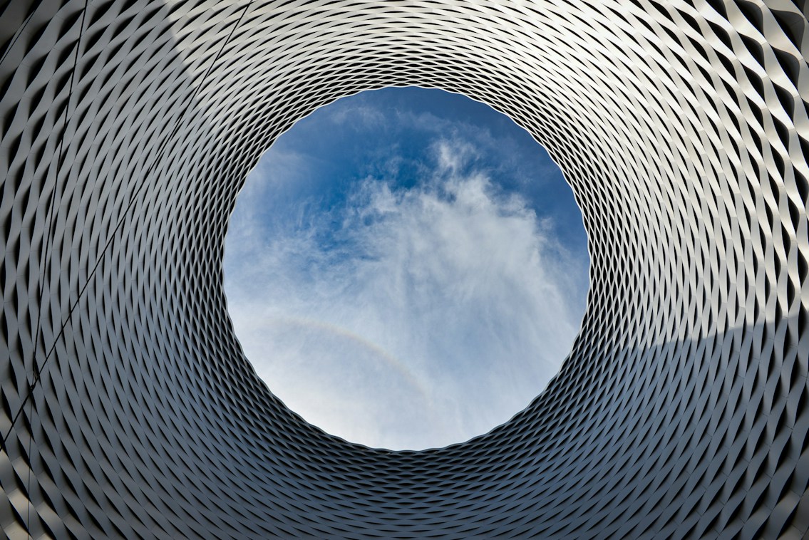 Looking up through a circular architectural opening at the sky